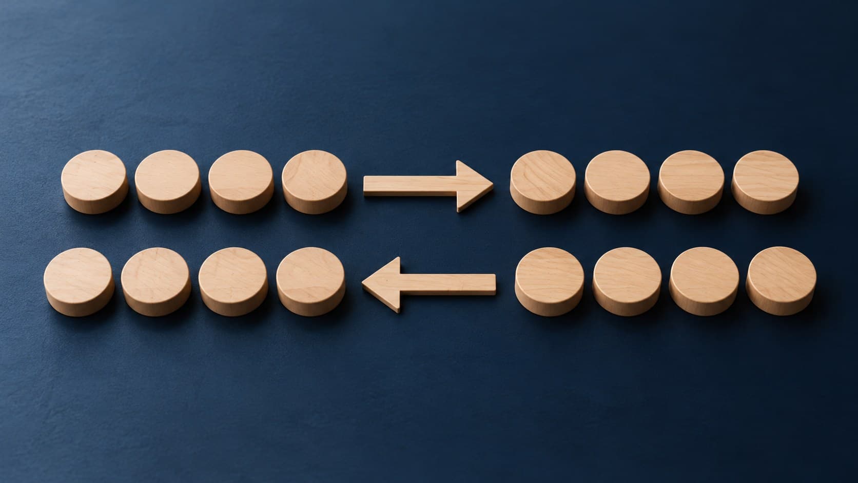 Two parallel rows of plain wooden discs with arrows pointing in opposite directions on a navy surface.